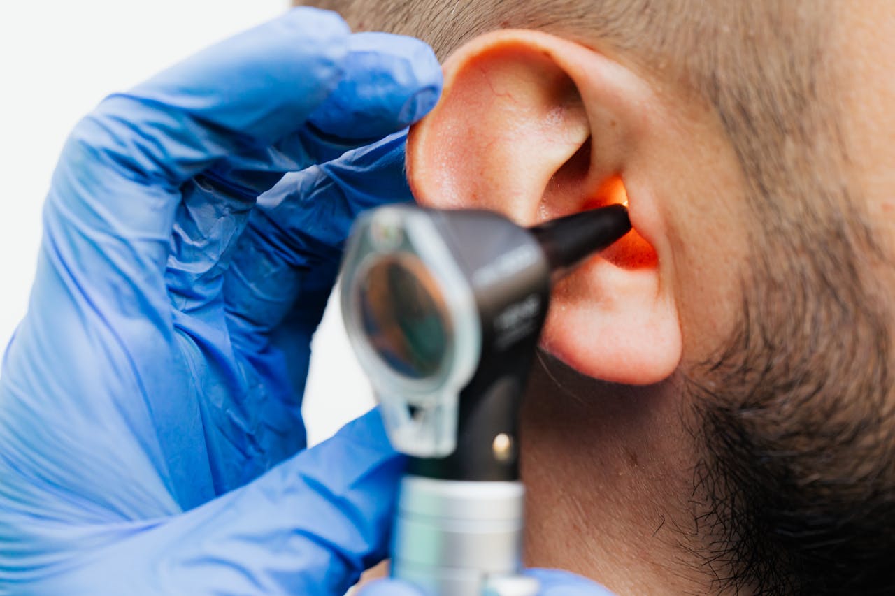 how-it-works Close-up of a doctor using an otoscope to examine a patients ear in a clinical setting.